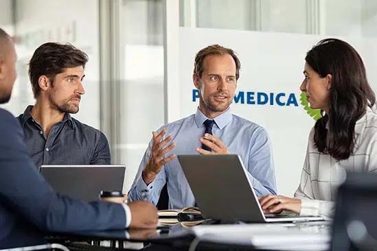 vier Personen im Meetingraum von Promedica Plus sprechen miteinander