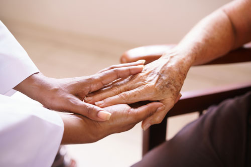 Frau hält die Hand einer Seniorin