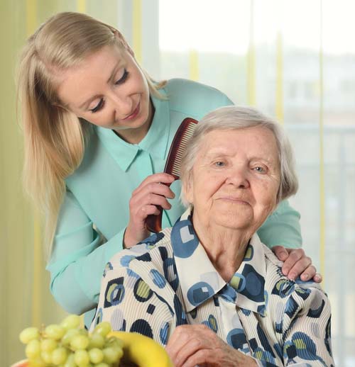Frau kämmt die Haare einer Seniorin