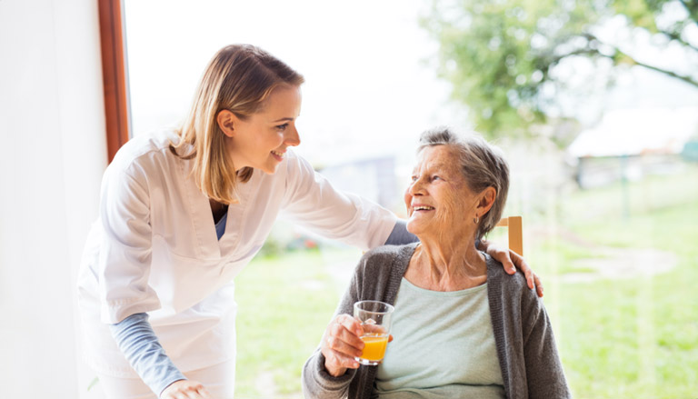 EIne Pflegekraft kümmert sich liebevoll um eine Seniorin.