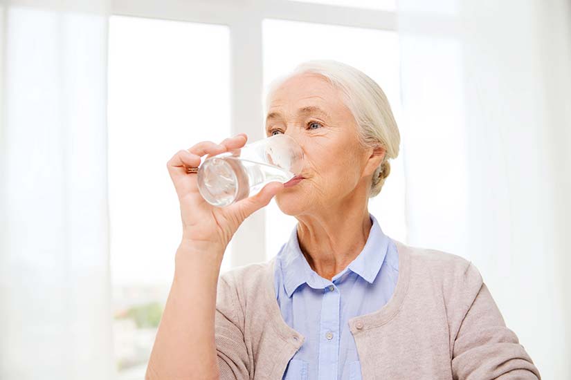 Senioren trinkt ein Glas Wasser.