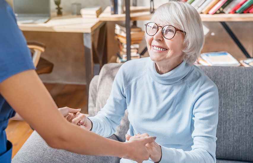 Betreuungskraft hilft Seniorin beim Aufstehen