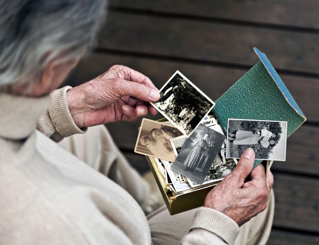 Eine Seniorin hält alte Fotos in der Hand