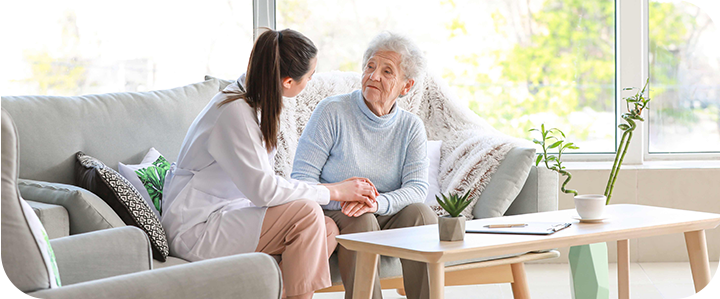 Seniorin und Betreuerin auf dem Sofa im Gespräch