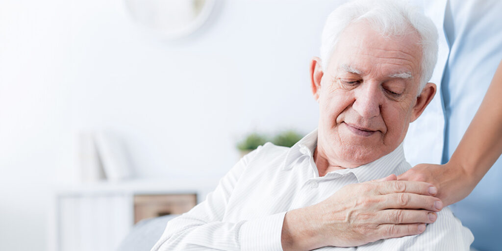 Ältere Mann berührt die Hand einer Pflegerin 