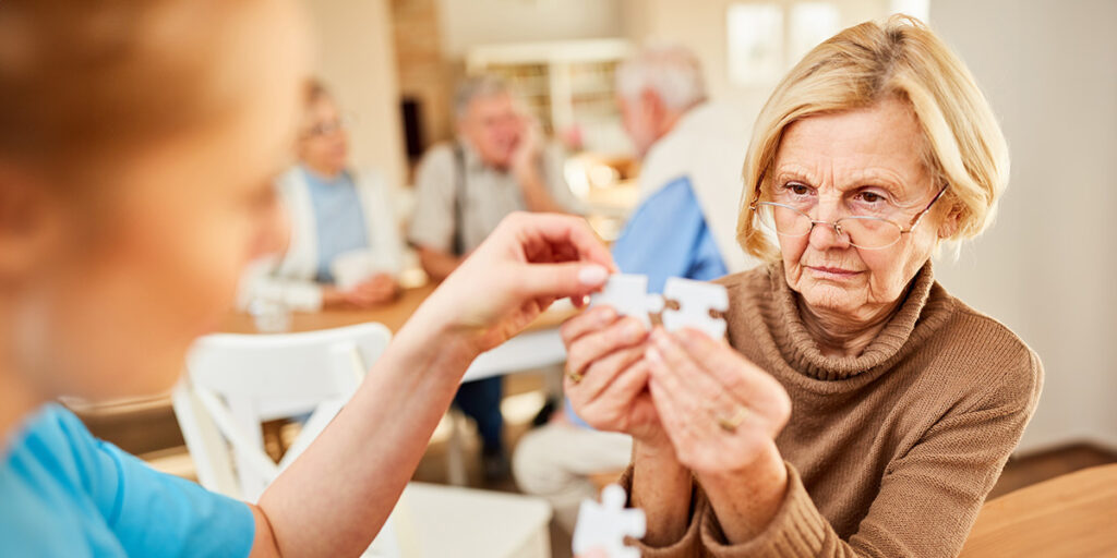 Oma puzzlet konzentriert mit Pflegekraft