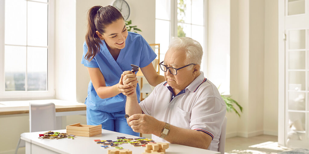 Älterer Mann puzzelt mit einer Betreuungskraft